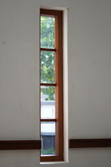 A long window with wooden lines against a white wall exposed to the morning sunlight