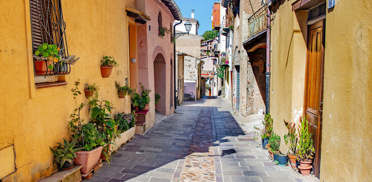 paved street crossing an old village with facades of colorful houses seui sardaigne italy