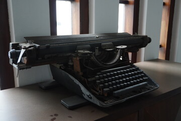 An old-fashioned typewriter placed on a table near a tall window
