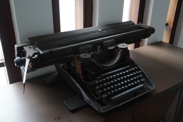 An old-fashioned typewriter placed on a table near a tall window