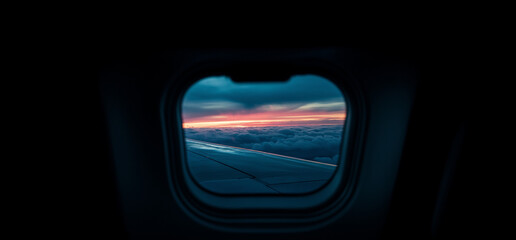 Stunning Airplane Window View – Fluffy White Clouds, Radiant Sunrise or Sunset, and Airplane Wing Soaring Towards the Horizon, Evoking a Sense of Freedom and Adventure