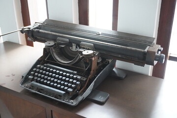 An old-fashioned typewriter placed on a table near a tall window