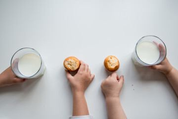 Childrens snack time with milk and muffins on white table