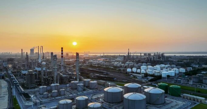 aerial time lapse video of a large petrochemical refinery by river at sunset