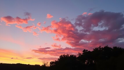 Fototapeta premium A Gorgeous Sunset View of Clouds Above a Forest with Orange, Pink, and Purple Hues in the Sky