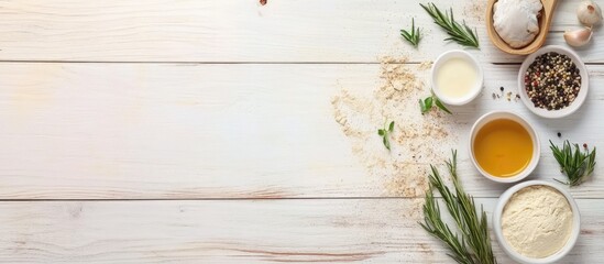 Homemade pizza ingredients on white wooden table with bowls of flour oil herbs and spices arranged on the left side of the image