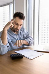 Focused man controlling incomes and earnings, check taxes and summary to pay, calculates expenses...