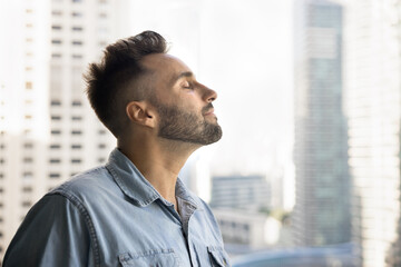 Close up profile face view of reflective, serene Hispanic man taking deep, calming breath, enjoy...