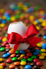 Easter egg with red bow close up with sweets on wooden table