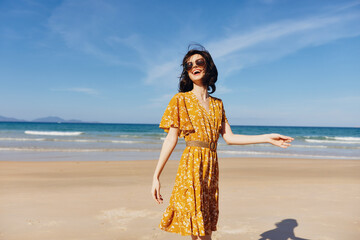 Woman in yellow dress enjoying the freedom of the beach with arms raised in the air