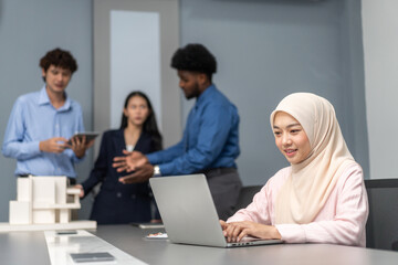 Muslim businesswoman in a hijab working on a laptop in a modern office, professional muslim woman, successful female leader in corporate environment, technology and teamwork in workplace diversity
