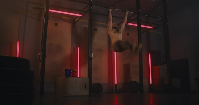 An athlete performs a difficult exercise on the horizontal bar in a modern gym with neon lights
