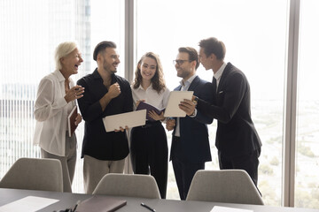Synergy in teamwork. Enthusiastic friendly diverse age business team hold lively discussion stand...