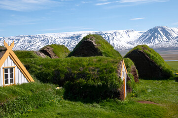 Skagafjordur Iceland, turf house with snow capped mountain in background