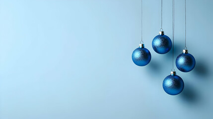 Four Blue Christmas Ornaments Hanging Against a Light Blue Background with Sparkling Decorations