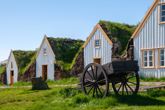 Skagafjordur Iceland, turf houses in a row with farm cart in foreground