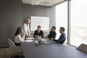 Business education. Senior businesswoman experienced trainer mentor coach teach young professionals group at team meeting explain case studies inspire innovative thinking on creative workshop training