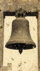 Obraz premium Vintage black and white photo of a cast-iron church bell in a stone arch. Sepia, aging effect, scuffs. The atmosphere of the past, retro style, historical setting.