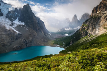 Fototapeta premium Turquoise Mountain Lake Surrounded by Snow-Capped Peaks and Lush Vegetation