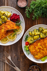 Breaded fried pork chop with fresh vegetable salad and potatoes on wooden table
