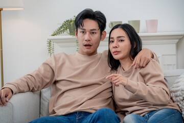 Obraz premium Young couple enjoying a cozy evening together in their living room while watching something captivating on the couch