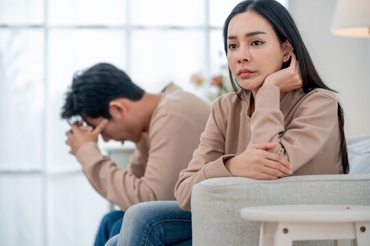 Couple sitting in silence during emotional conflict in a bright living room setting in the afternoon