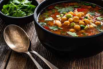Fresh vegetable soup with chickpea on wooden table
