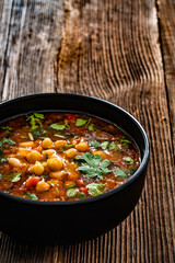 Fresh vegetable soup with chickpea on wooden table
