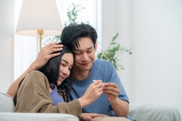 A happy couple sits together with a pug resting on their laps, showcasing an ultrasound image with smiles. The warm atmosphere captures their excitement about expecting a baby.