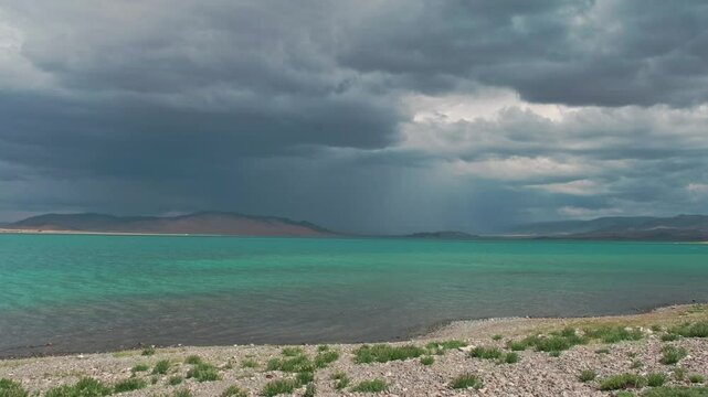 View of a beautiful lake in the Mongolian desert. A lake with a view of sand dunes and an impending storm. Reservoir in the Gobbi desert.