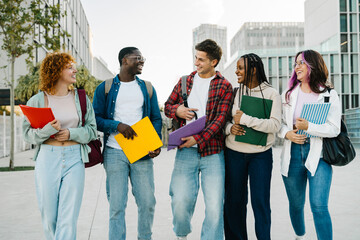 Group of diverse university student friends walking going to classes on college campus. Diversity...