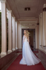 Fototapeta premium beautiful blonde bride in a beautiful hotel in an arch in a long wedding dress