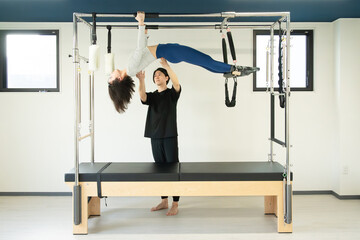 Fototapeta premium Pilates Cadillac Core Training with Professional Instructor Hanging Pull-Up 