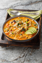Chicken Enchilada Soup is creamy, thick, very comforting, and delicious closeup on the plate on the table. Vertical