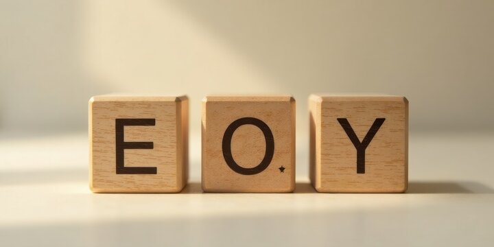 Wooden blocks spelling out the letters EOY in soft light