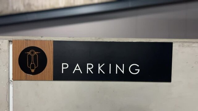 Close-up of &ldquo;Parking&rdquo; sign with motorbike icon, offering clear guidance for motorcycle parking in a public space.
