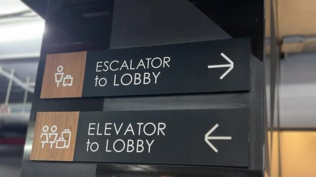 Close-up of &ldquo;Escalator to Lobby&rdquo; and &ldquo;Elevator to Lobby&rdquo; sign with icons and arrows for clear wayfinding.
