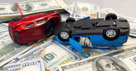 Toy cars in acciden on a background of 100 dollar bills