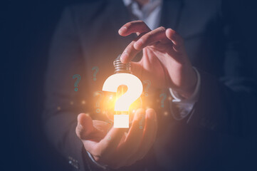 Businessman holding virtual light bulb in concept of idea Question mark concept. Problem and...