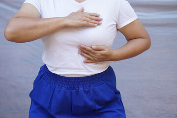 Close up woman uses hands to touch or massage her breast. Concept, self-checking breast cancer. Inspect abnormal of disease screening individually . Woman health care.       