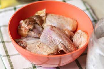 Chicken wings in a bowl sprinkled with coarse salt and black pepper. The wings appear fresh and are ready for marination. The seasoning. Preparation for cooking. Hight quality photo