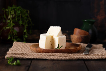Caciotta Tuscan italian fresh delicate cheese on olive wooden plate.
