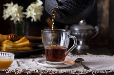 Morning hot drink black tea in glass cup for breakfast, old vintage style.
