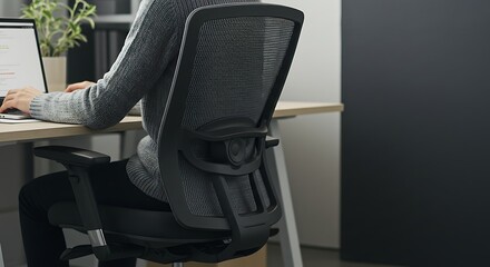 A professional young woman adjusting her chair for better ergonomics as she prepares to work on her computer in the office

