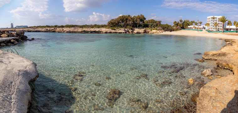 Panoramic view of the quiet Latchi Beach near Ayia Napa, Cyprus. Crystal clear turquoise water and rocky coastline during a sunny winter morning in December. Scenic Mediterranean seascape.