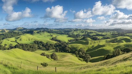 Obraz premium A picturesque panoramic shot of rolling green hills under a radiant blue sky, dotted with soft white clouds floating peacefully above
