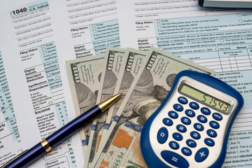 tax forms, calculator, pen dollar money on desk. View from above. Time for tax