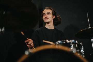 Young drummer performing during a band rehearsal in a music studio