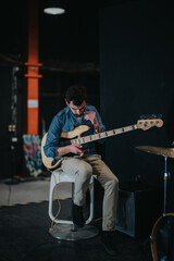 A musician practices playing an electric bass guitar while rehearsing in a music studio. The scene...