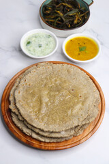Roti and Sabzi. Indian vegetarian Thali includes bhindi fry, yellow daal tadka, cucumber raita, and jawari or Jowar bhakri. Indian food is served in a plate or thali. Copy Space. healthy Veg Thali.